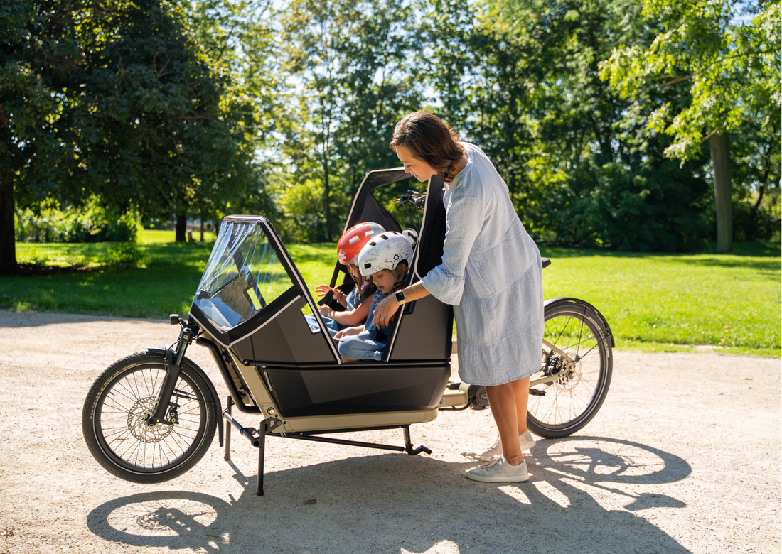 Erzieherin transportiert zwei Kinder sicher und bequem im Cargobike im Kita-Alltag